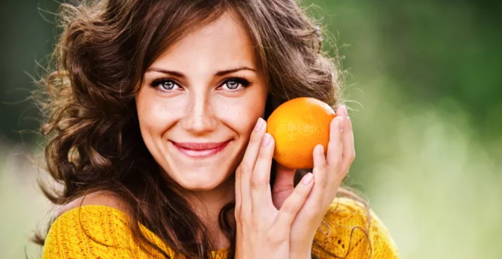 A woman holding an orange in her hands.