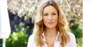 A woman with long blonde hair wearing a white shirt.