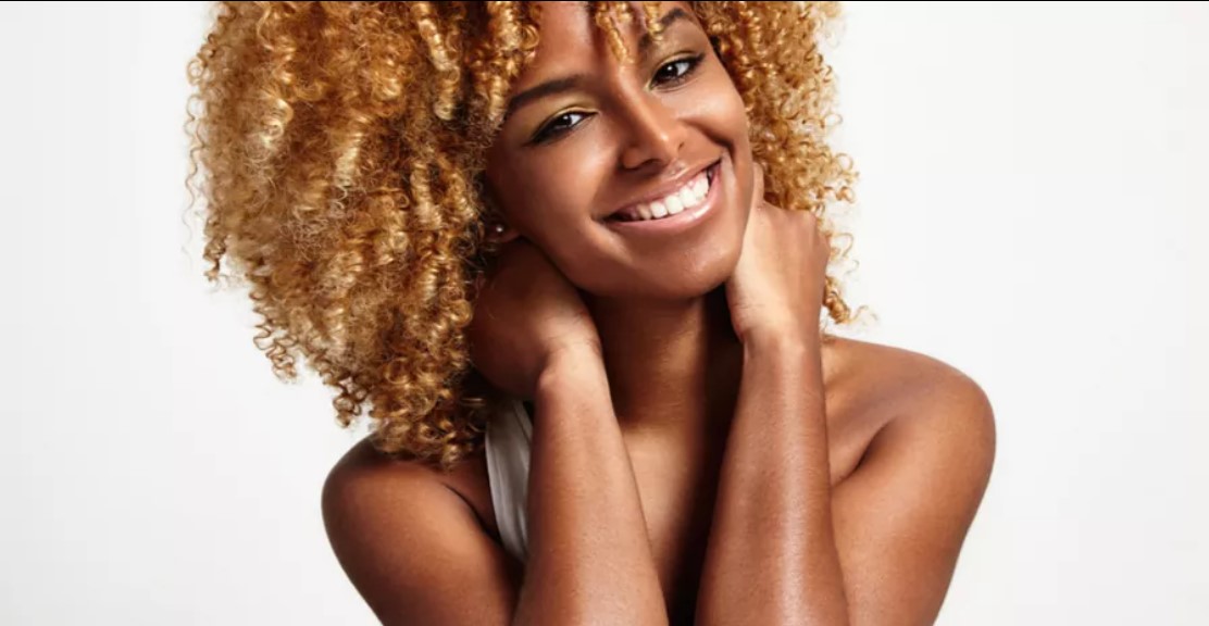 A woman with curly hair smiling for the camera.