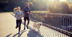 A man and woman running with their dog.