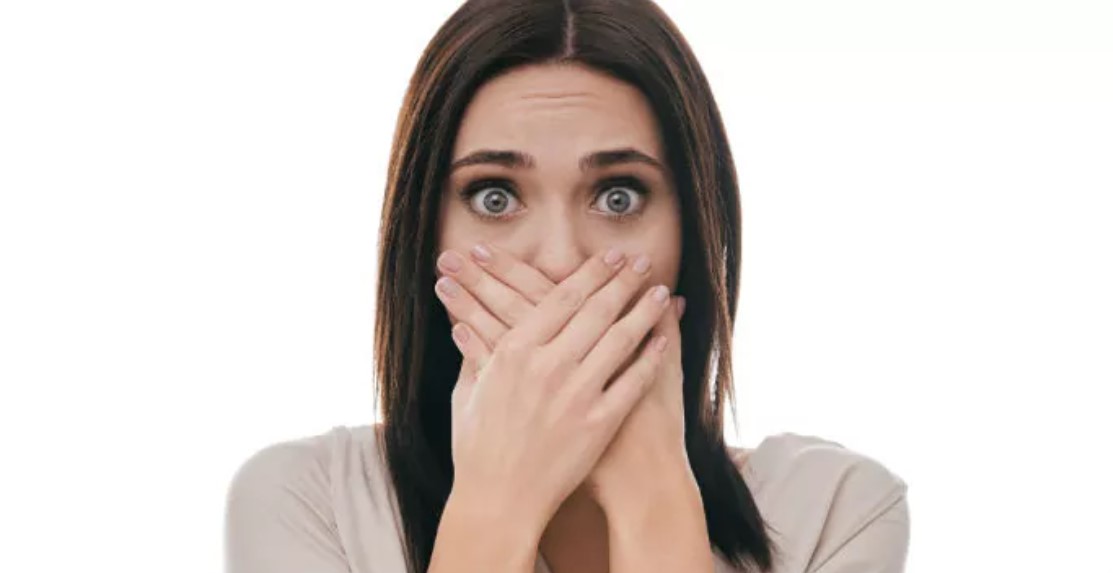 A woman covering her mouth with both hands.
