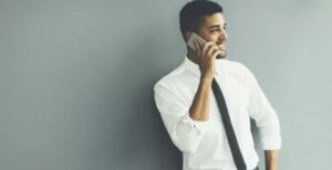 A man in white shirt and tie talking on phone.