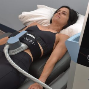 A woman laying on top of a bed with an electric device.