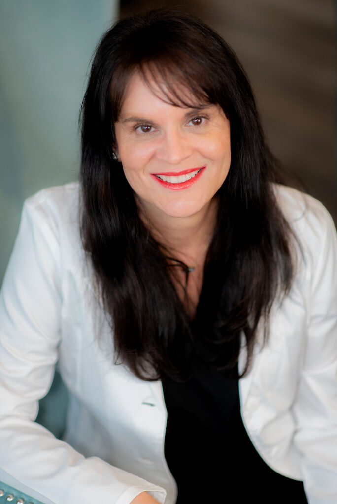 Smiling woman with dark hair and white lab coat.