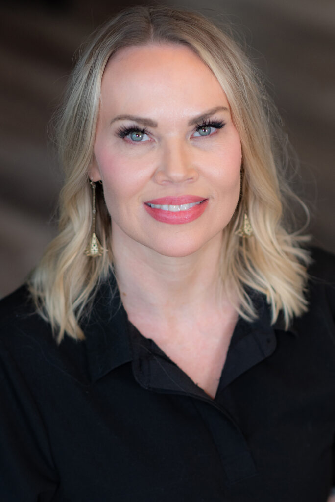 Woman with blonde hair smiling in black shirt.