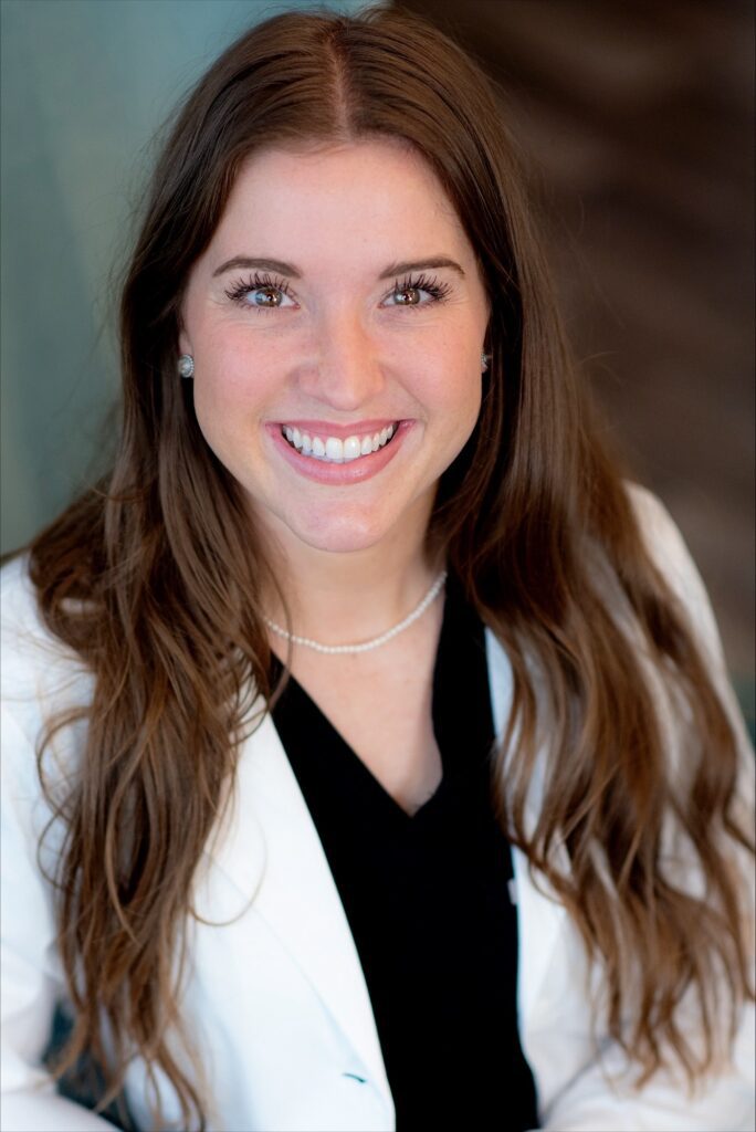 Smiling woman wearing a white lab coat.