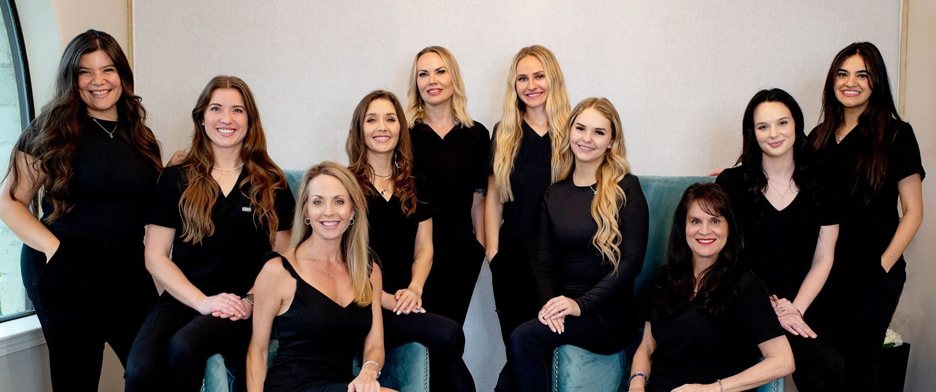 Group of women smiling in black attire.